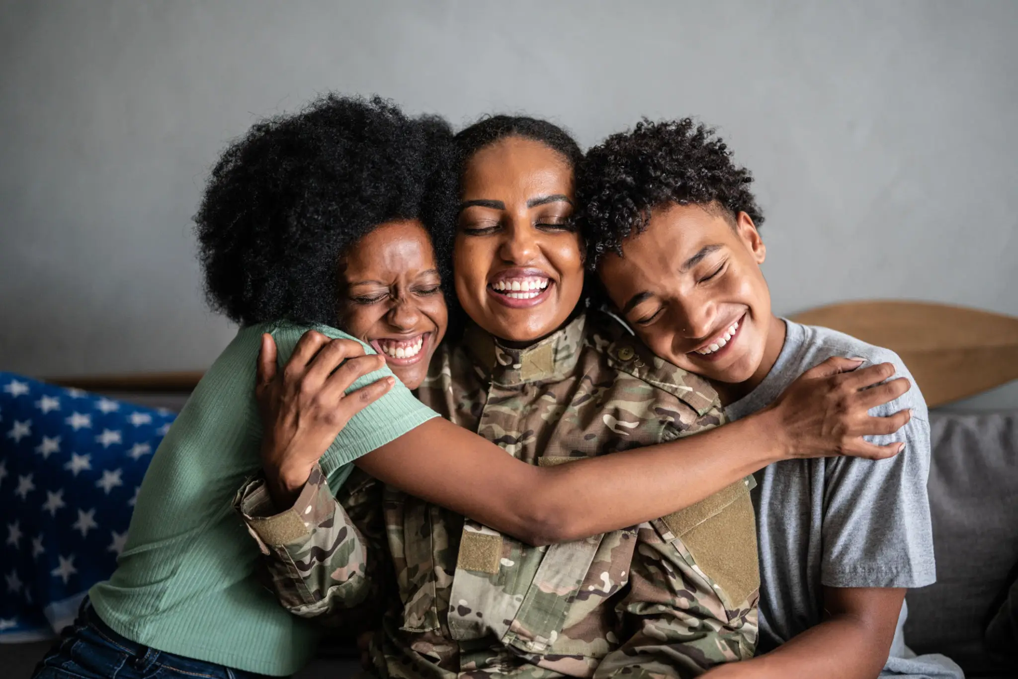 A soldier joyfully hugging two children outdoors.