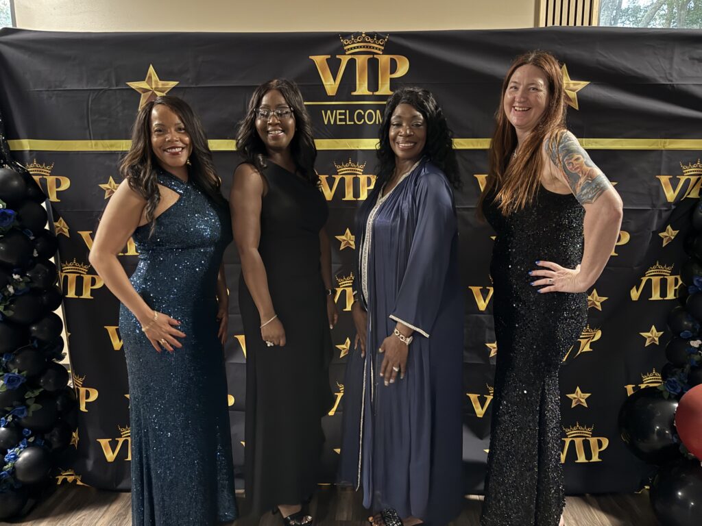 Four women dressed elegantly at a VIP event.