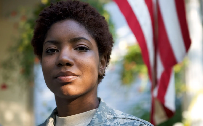 Confident soldier standing in front of the American flag.